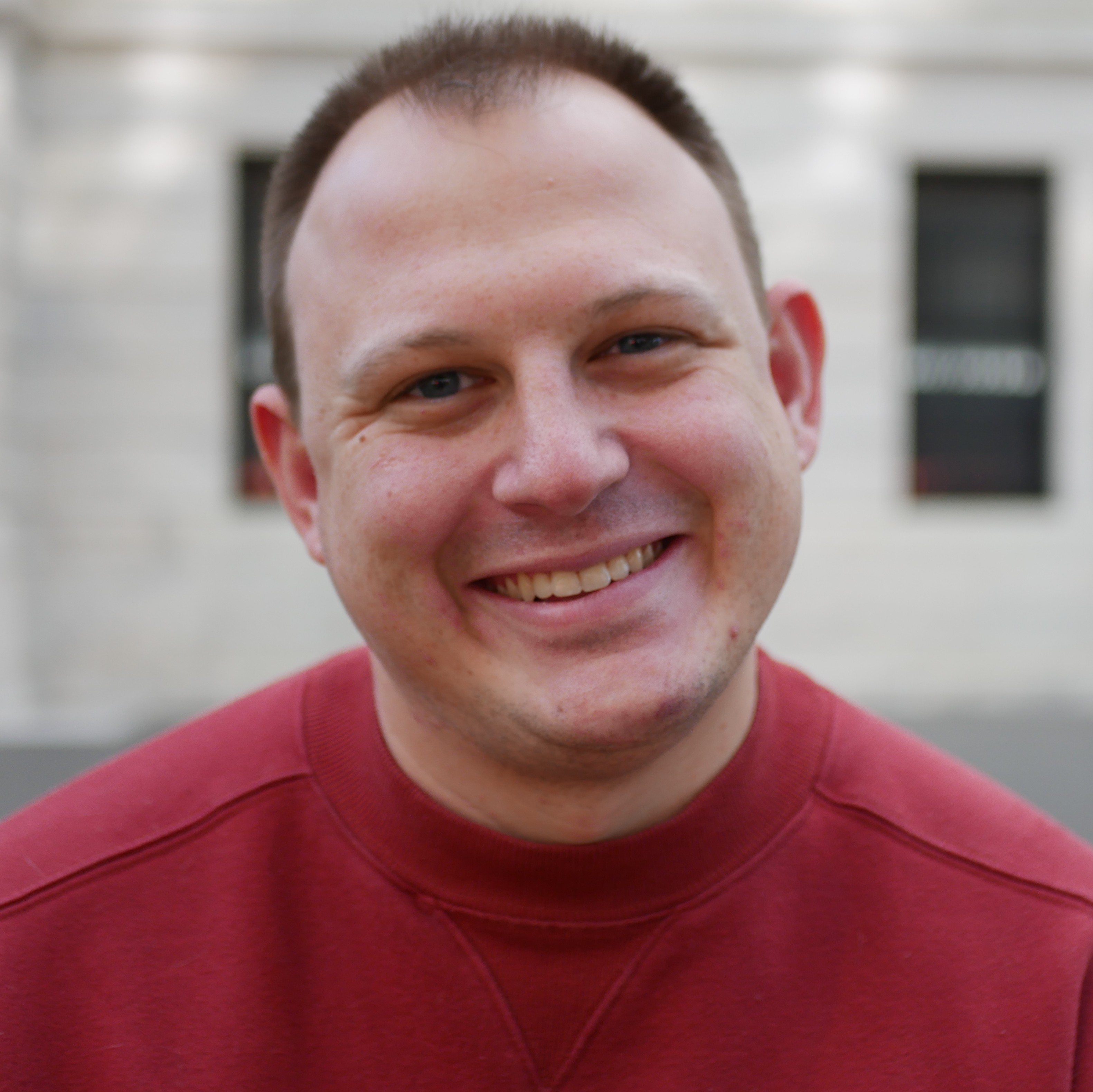 Picture of Peter Landoll wearing a red sweatshirt against a bright background